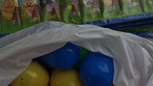 Bunte Plastikostereier und eingepackte Schokoladenlutscher mit osterlichem Motiv.